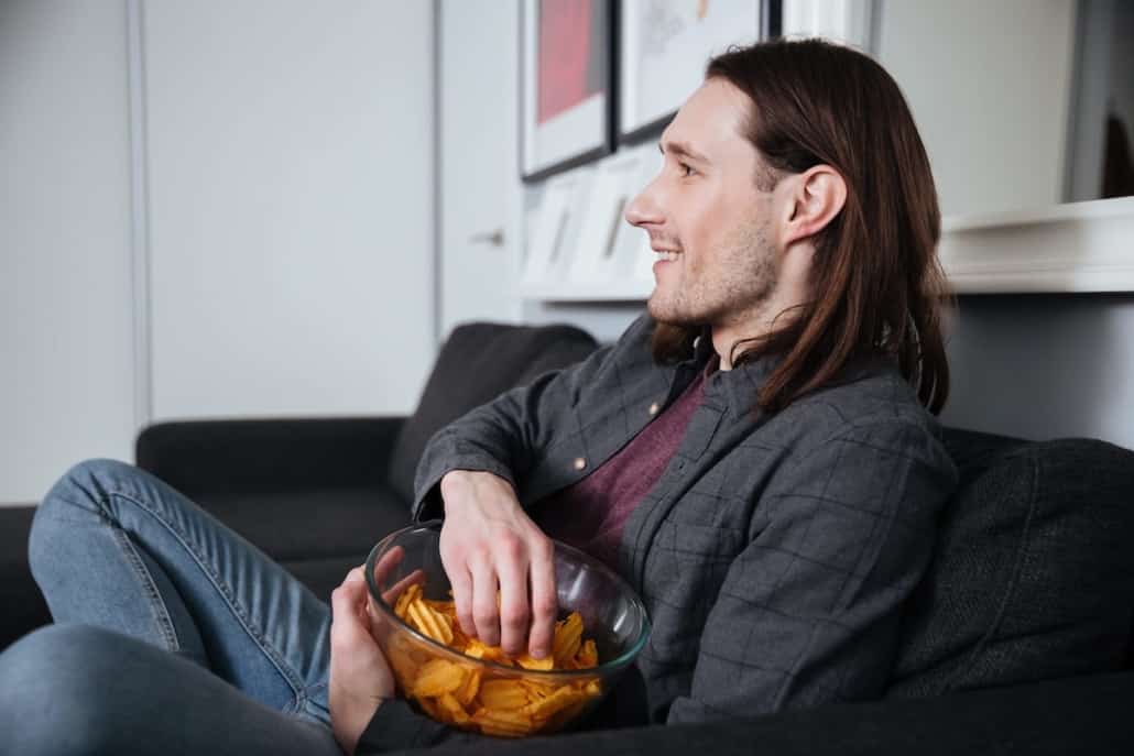 man sitting at home indoors eating crisps